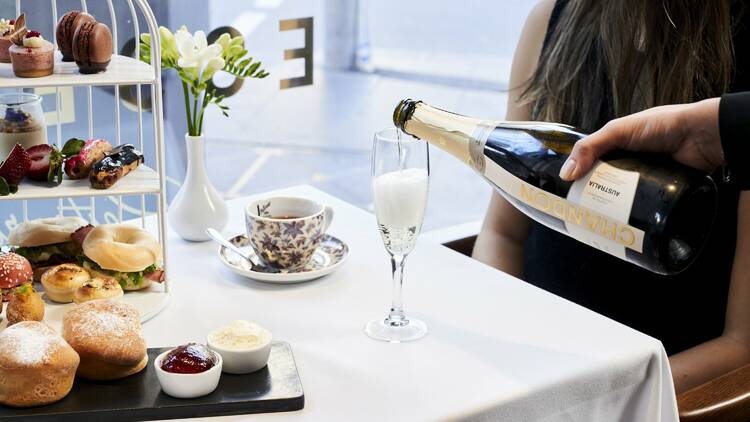 A waiter pouring sparkling wine at Marriott Hotel's high tea experience.