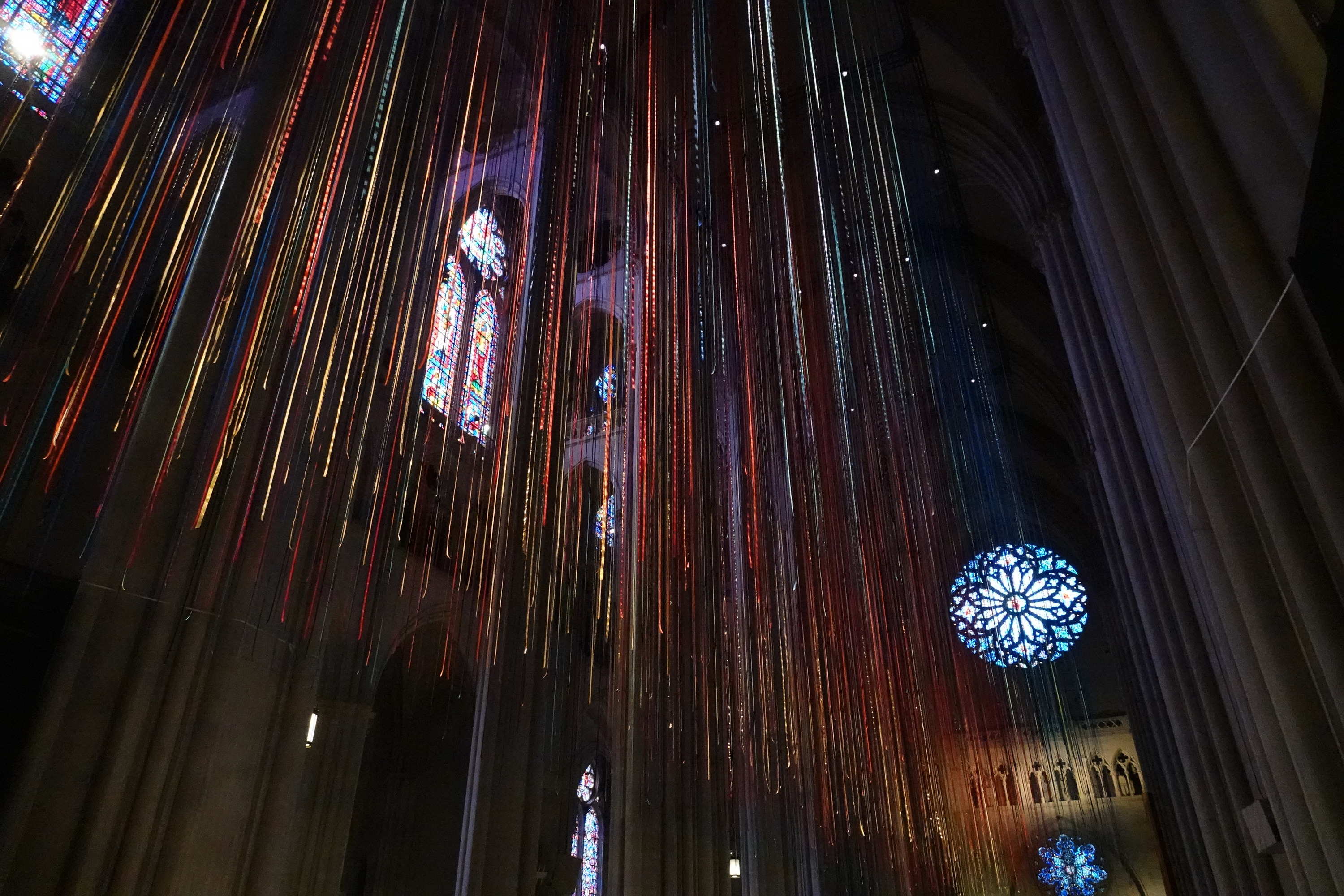 Ribbons hang in a church with stained glass windows behind them.