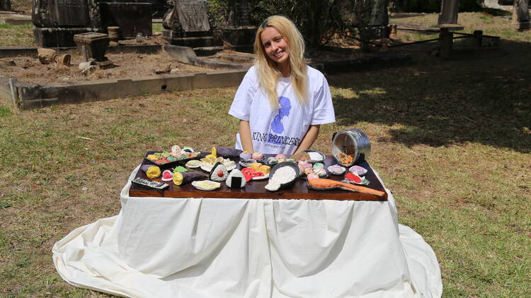 A photo of a girl pictured with a Japanese banquet sculpture in a cemetery.