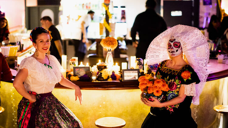 Two women in Día de Muertos outfits.