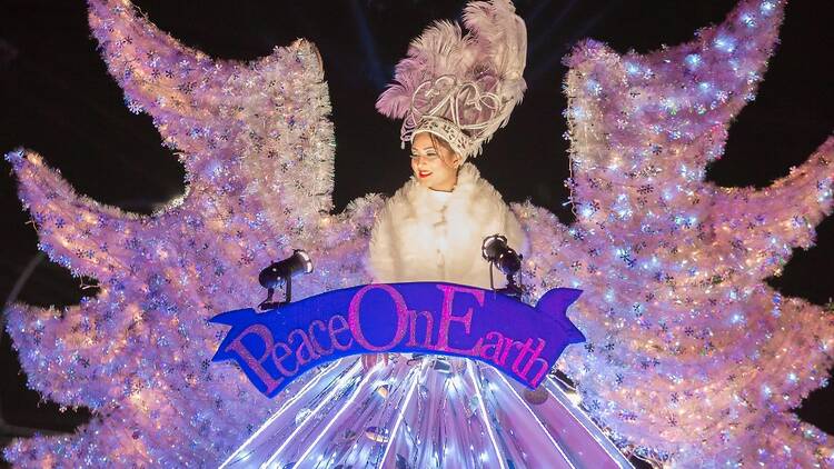 A woman dressed up in an angelic costume reading "Peace on Earth."