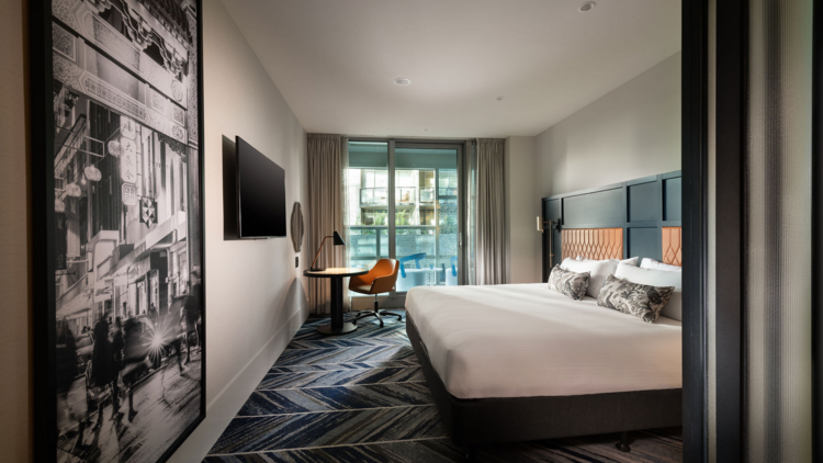 Room at Dorsett Melbourne with patterned carpet and white bedding