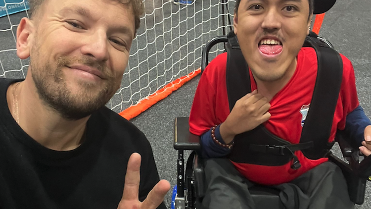 Dylan Alcott poses with a young person in a wheelchair. 