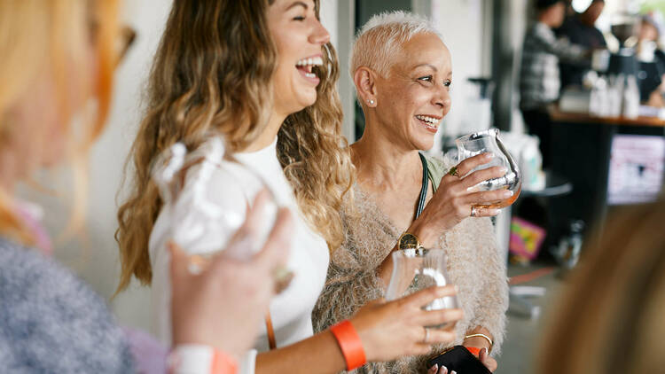 Women laughing while tasting wine at a Fresh Blood event.