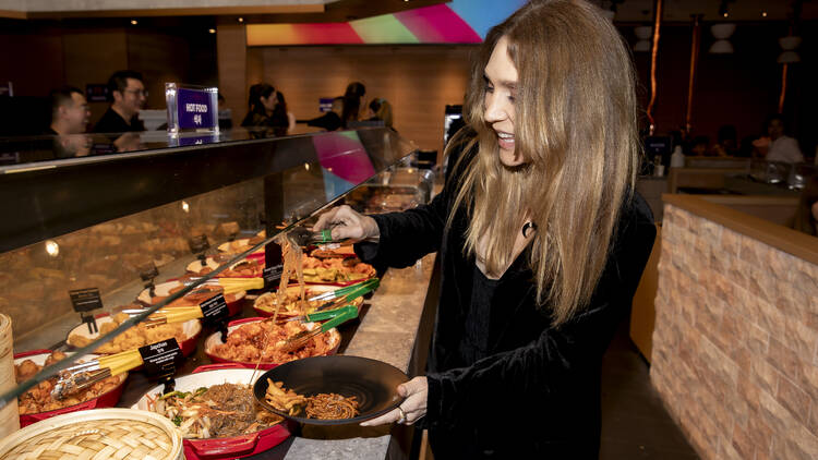 Woman helping herself from a Korean all-you-can-eat buffet.
