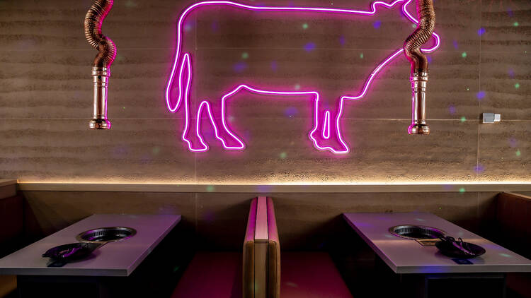 Neon pink cow-shaped light on the wall at Seoul Garden. 