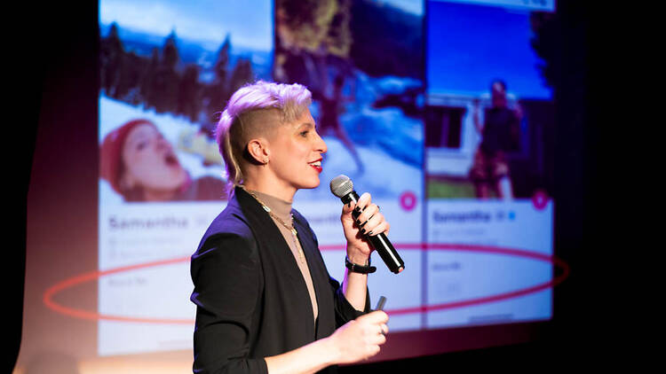 A performer holds a mic in front of a screen.