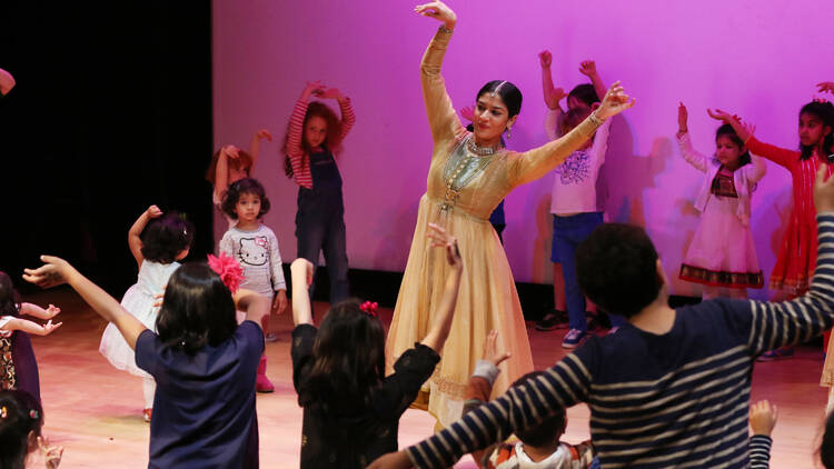 A woman dances with kids at a Diwali event.