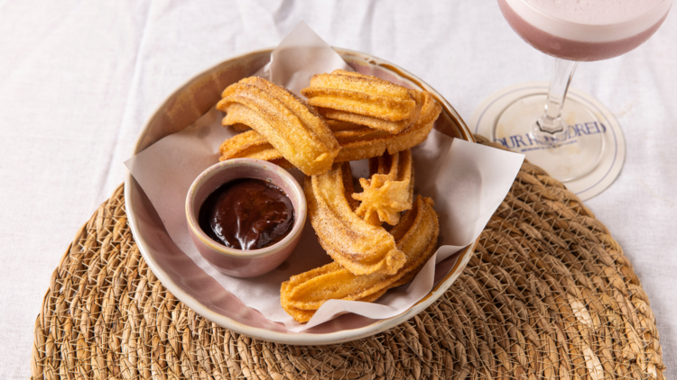 Churros with a tub of chocolate in a pink bowl