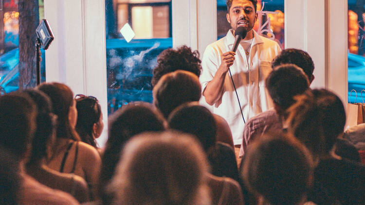 A comedian stands in front of a crowd with a mic.