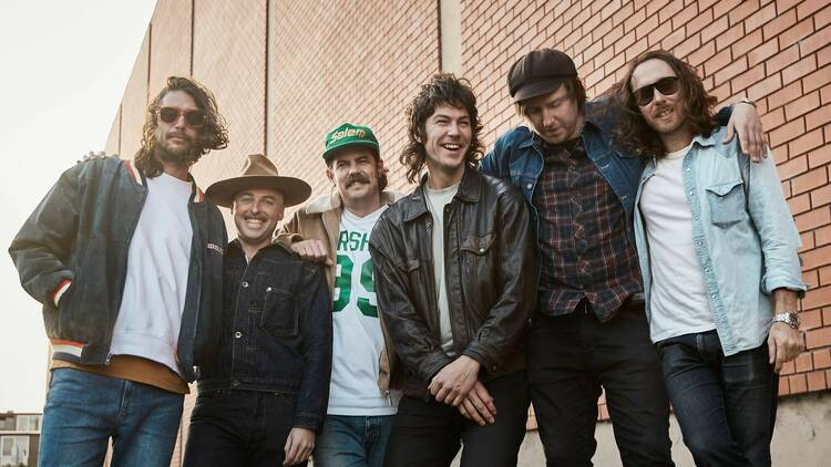 Six band members in front of a brick building