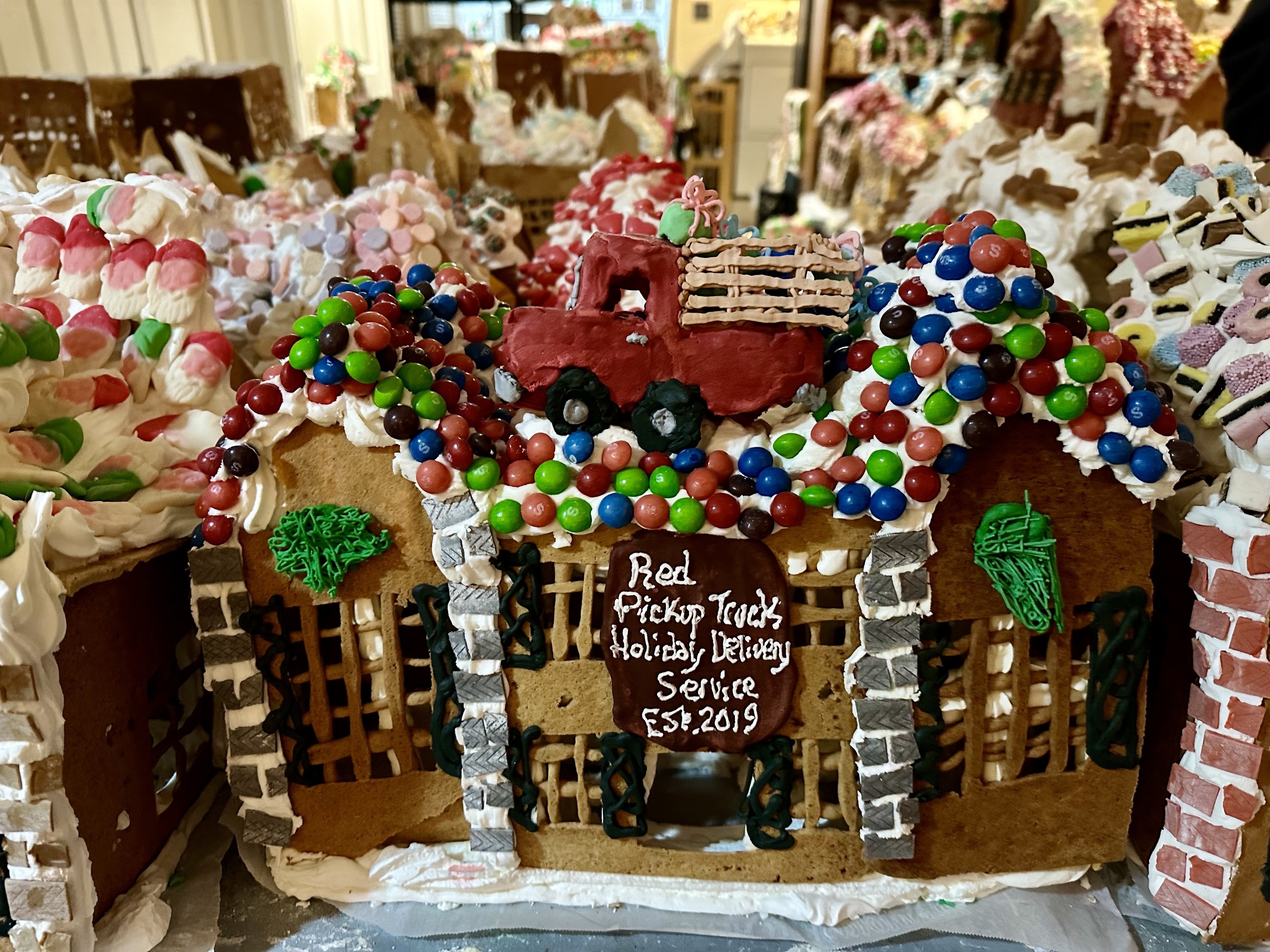 A gingerbread house with a tiny red truck.