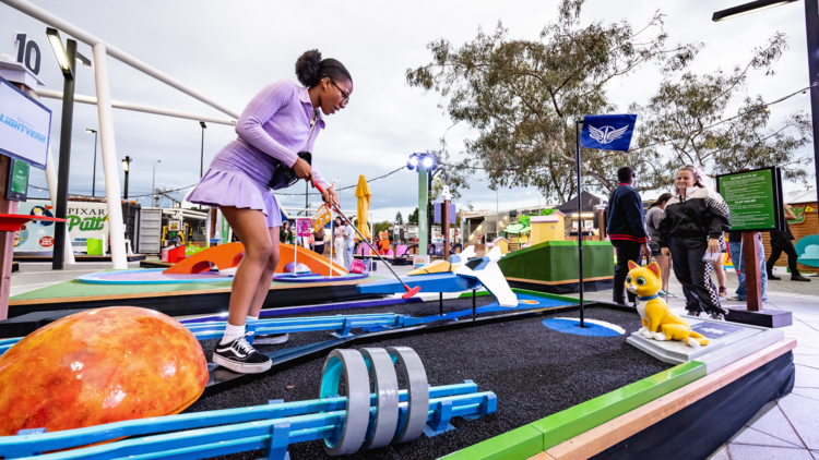 Girl playing Pixar themed mini golf