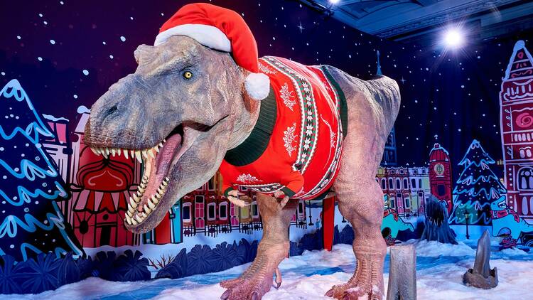 A T-Rex wearing a red Christmas jumper and Santa hat at the Natural History Museum