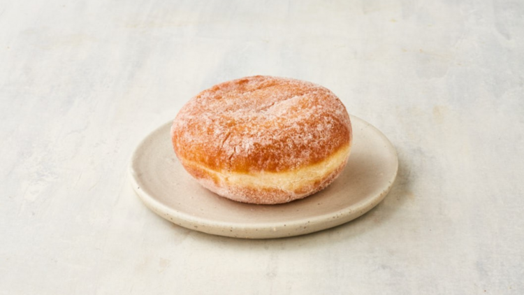 A jam ball donut on a small off-white plate