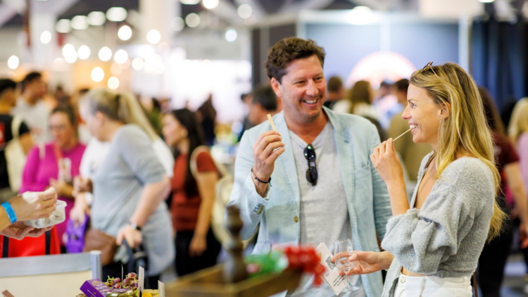 People eating bread sticks at a wine and food market