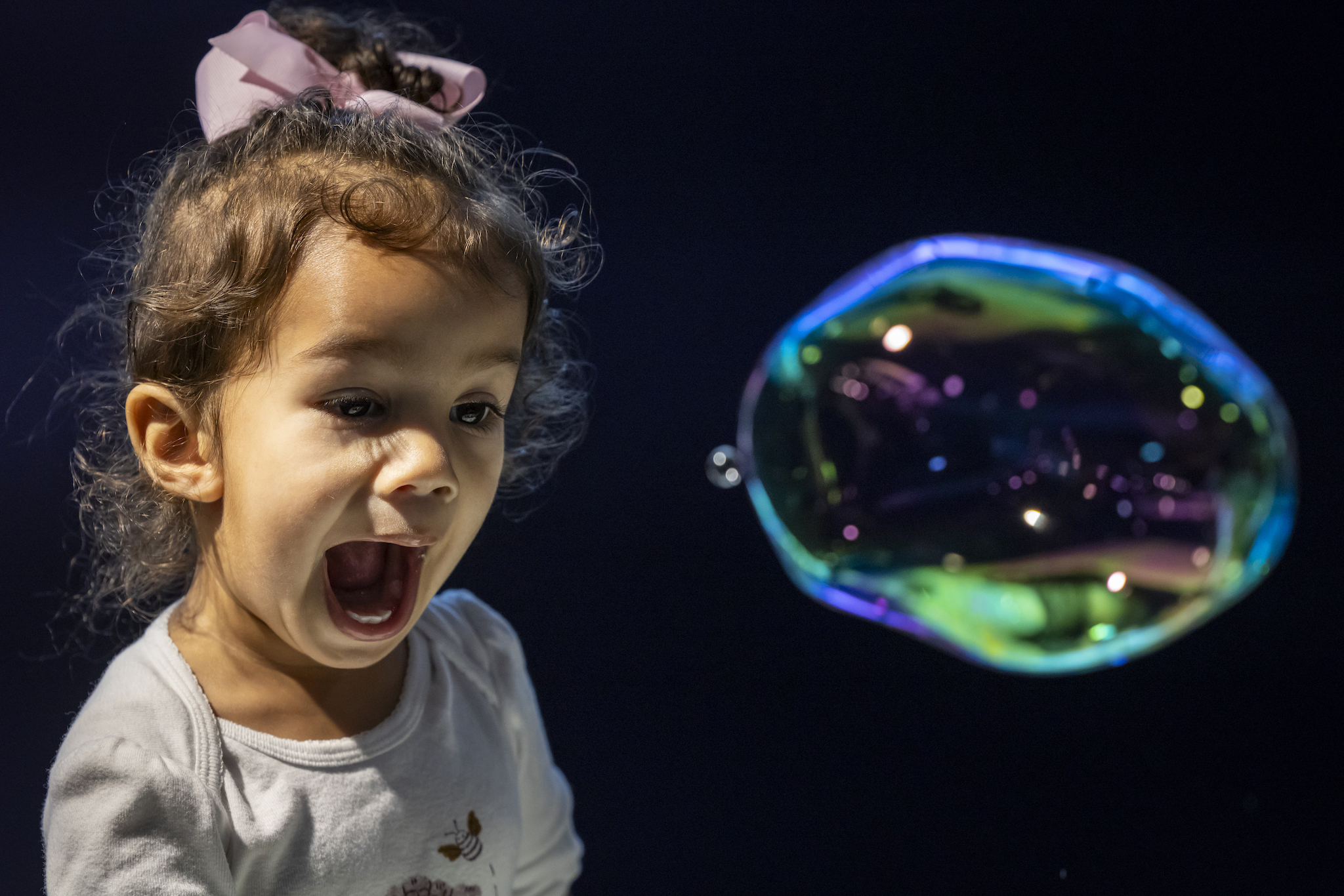 A child looks at a bubble with glee.