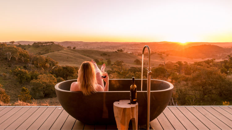 person in outdoor bath at sunset at sierra escape mudgee