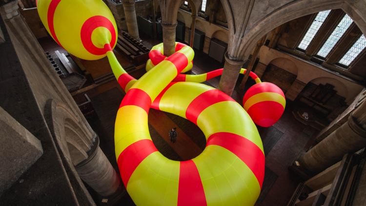 A large yellow and red snake scultpure in a warehouse