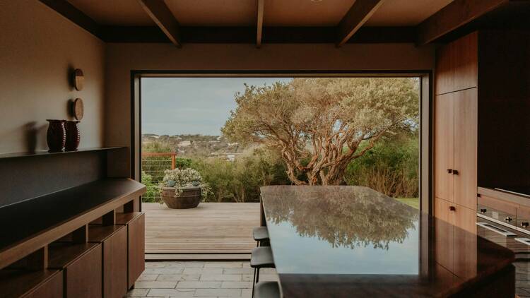 A kitchen with an island bench and view out to a green landscape. 