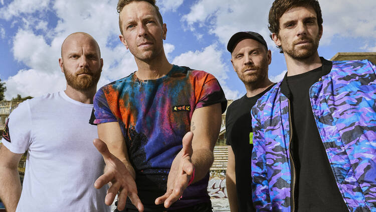 The band Coldplay posing against a blue sky backdrop.