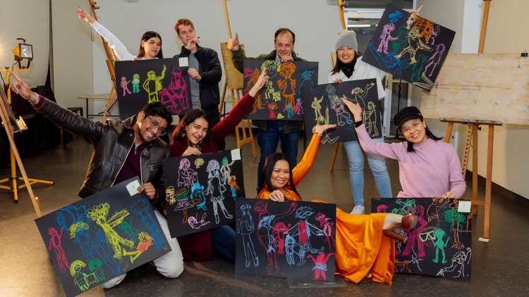 A group of artists holding their paintings