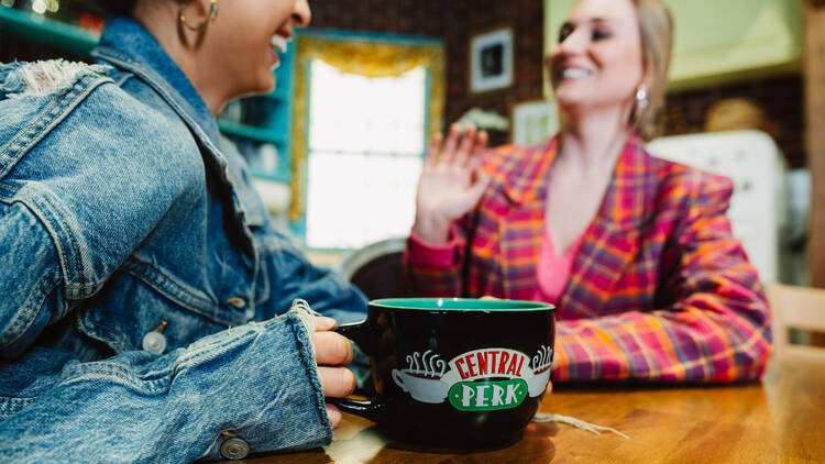 Two women with a Central Perk mug.