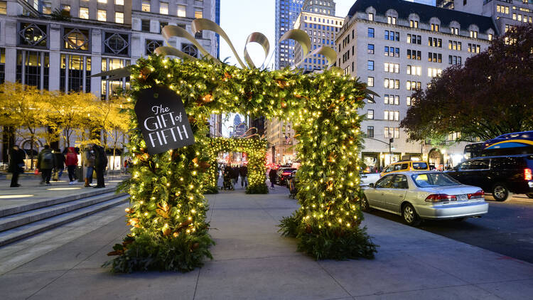 An evergreen archway lit with Christmas lights on Fifth Ave.