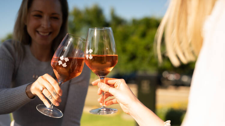 Two people holding wine glasses and making a cheers motion. 