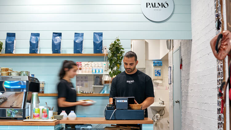 A blue cafe front counter with two staff