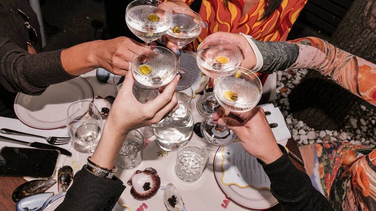A group of people cheersing with cocktails.