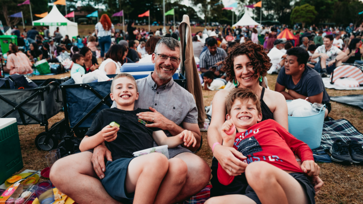 A family at a festival sitting in the park