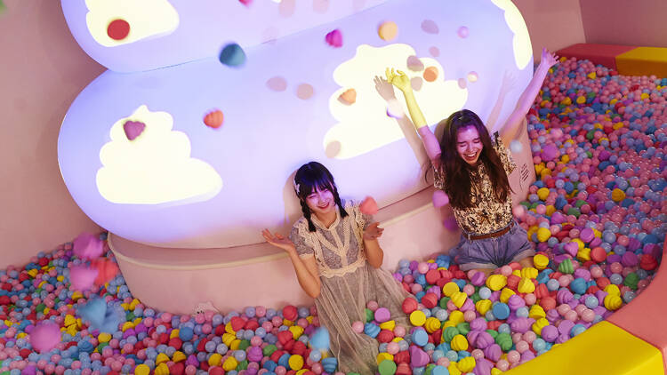 Two people in a colourful ball pit. 