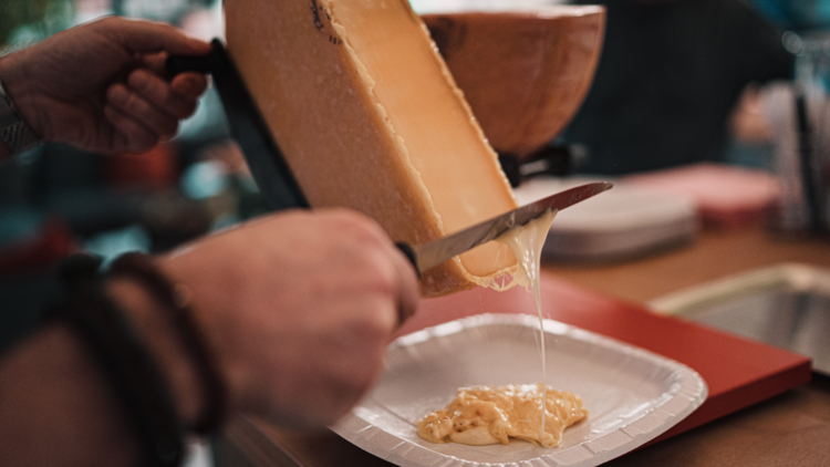 Raclette being dropped onto a plate