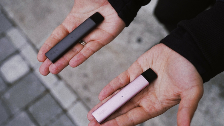 persons hands holding vapes