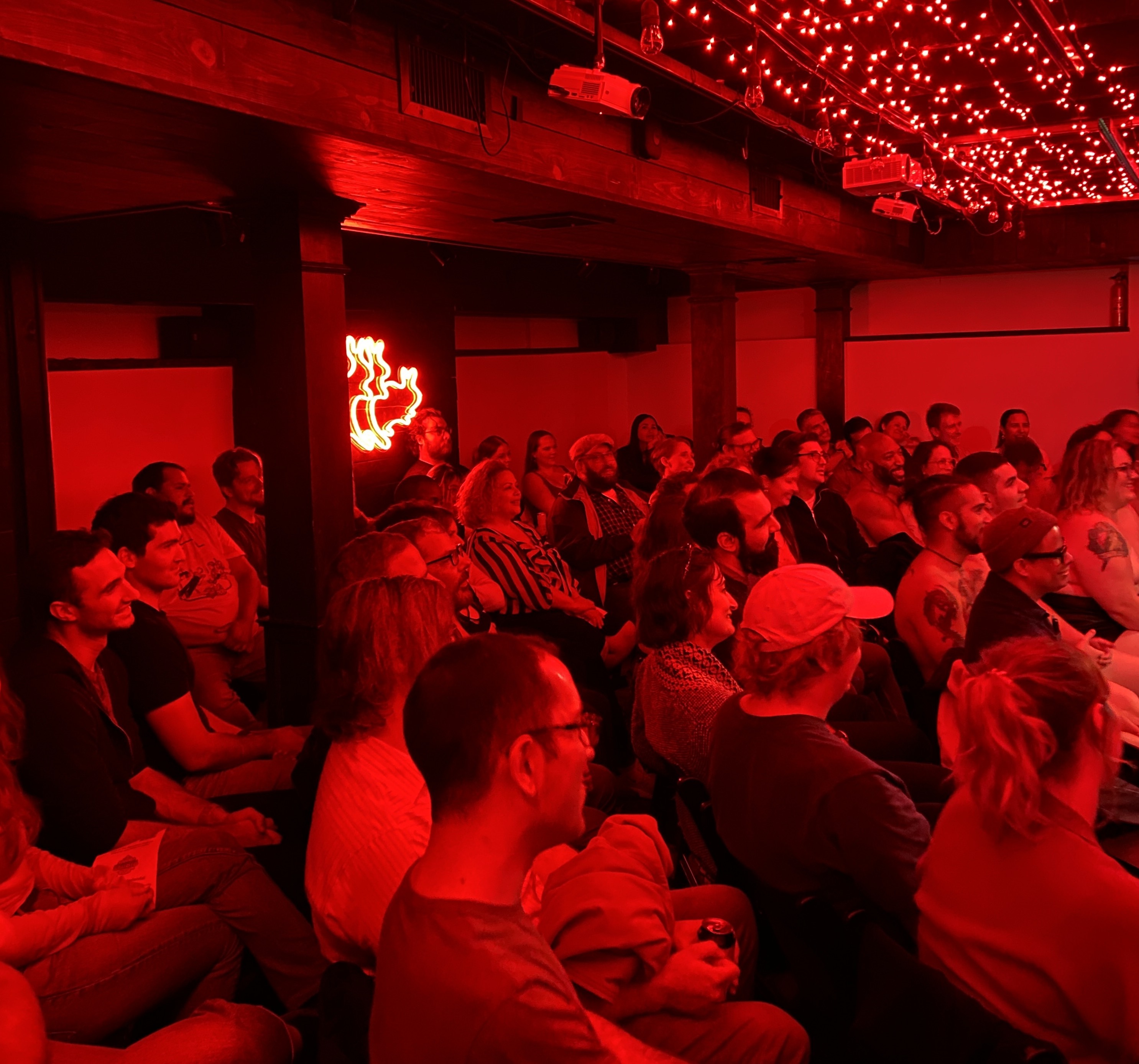 A crowd of people at a comedy show bathed in red light.