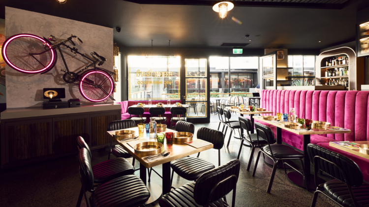 A dining room with a pink velvet banquet and a bike mounted on the wall