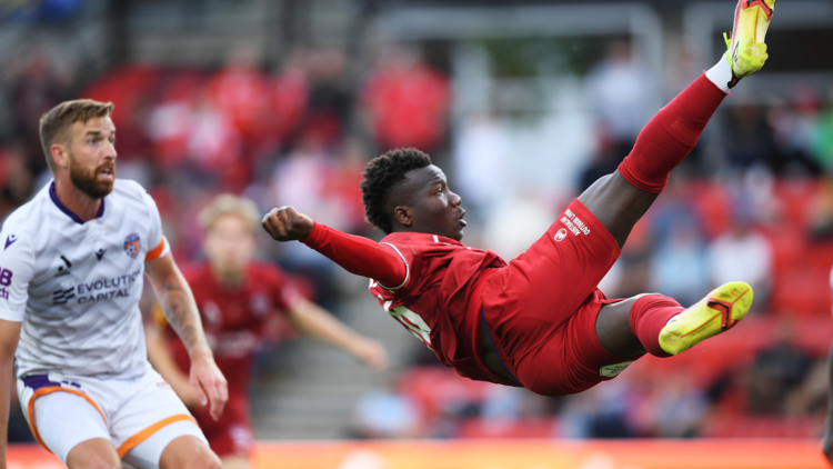 A red soccer player kicking mid air