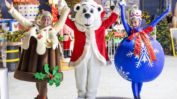Three performers dressed up as colourful Christmas characters. 