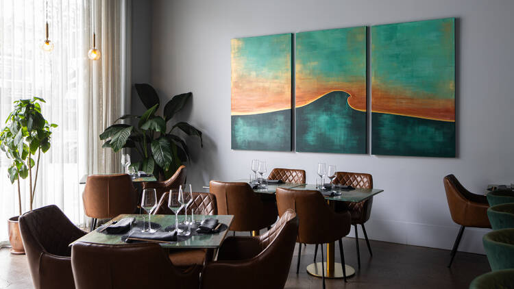 Clean modern dining space with greenery and large colourful artworks.