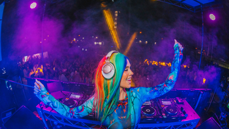 A rainbow haired DJ behind her decks