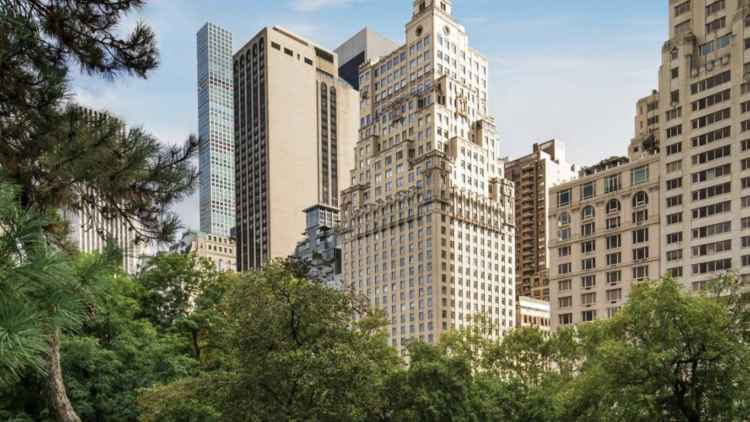 An exterior shot of the Ritz in New York, with green trees surrounding the hotel building.
