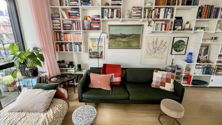 Apartment lounge with  a daybed, green sofa, built in bookshelf and artwork. 