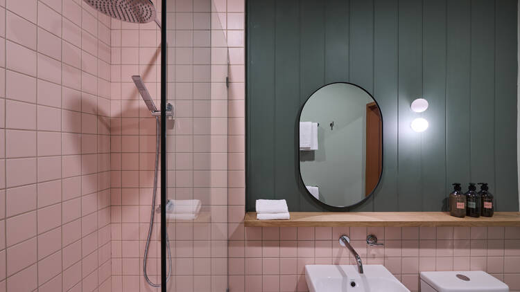 Pink-tiled bathroom with mirror and shower.