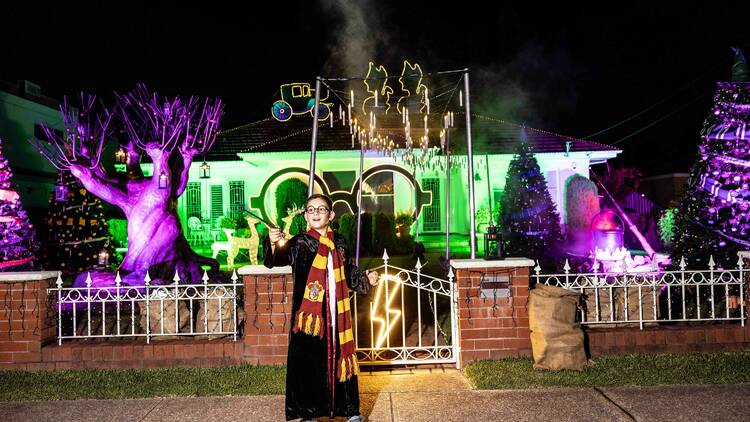 boy dressed as Harry Potter in front of Christmas light display