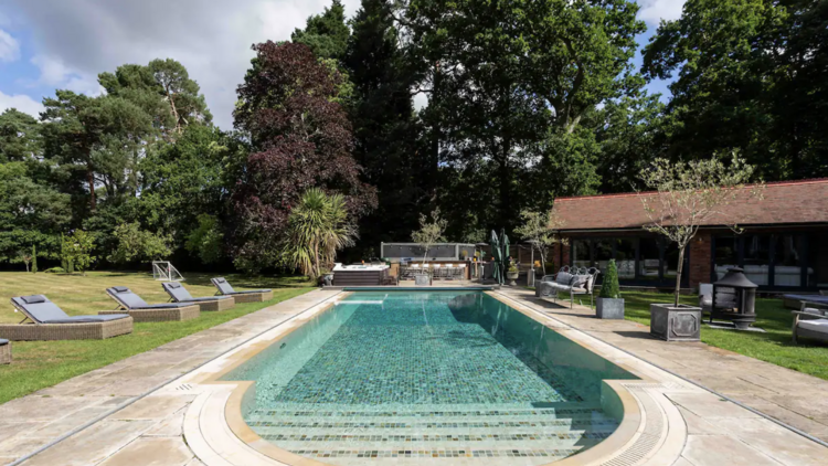 A large outdoor pool with numerous sun loungers at an Airbnb in Ascot, United Kingdom.