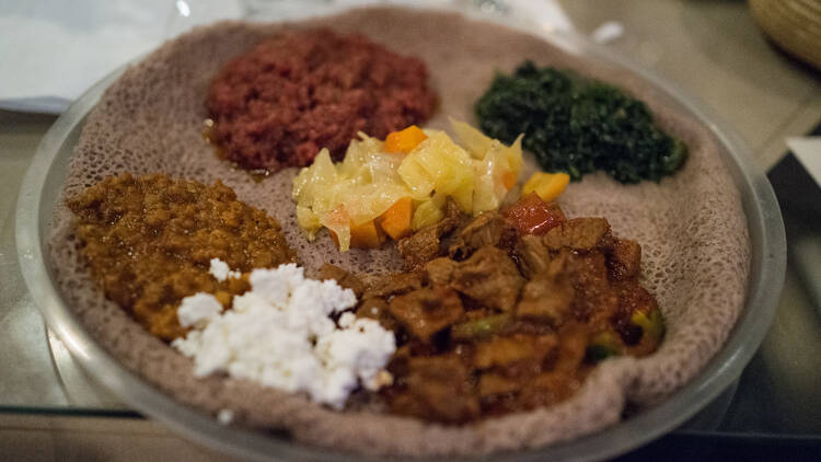 An assortment of traditional African stews served on a sponge-like bread.