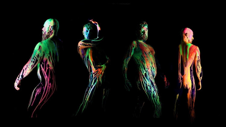 Four men posing in the dark with neon paint on their bodies