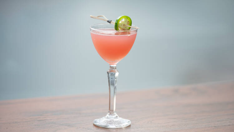 A pinky cocktail with a slice of jalapeno on top