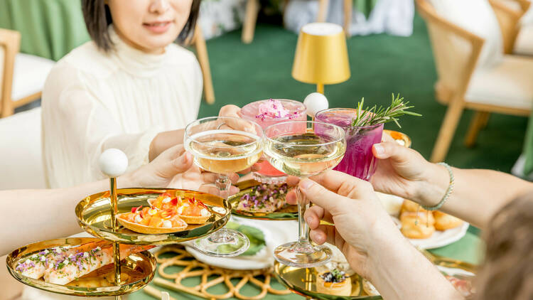 Women clinking cocktails at a high tea luncheon.